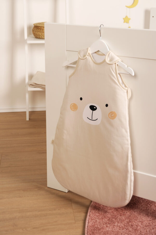 babybest Schlafsack Little bear hängt an weißem Bett mit einem Bügel