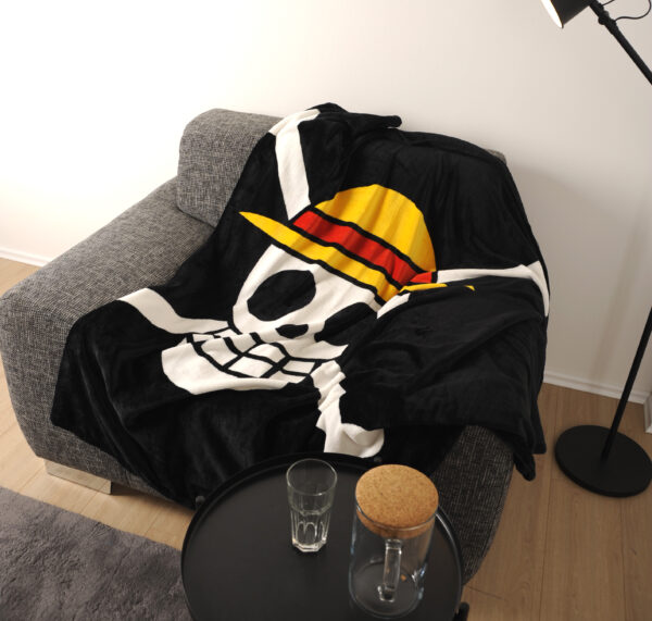One Piece Decke Skull liegt auf grauem Sessel