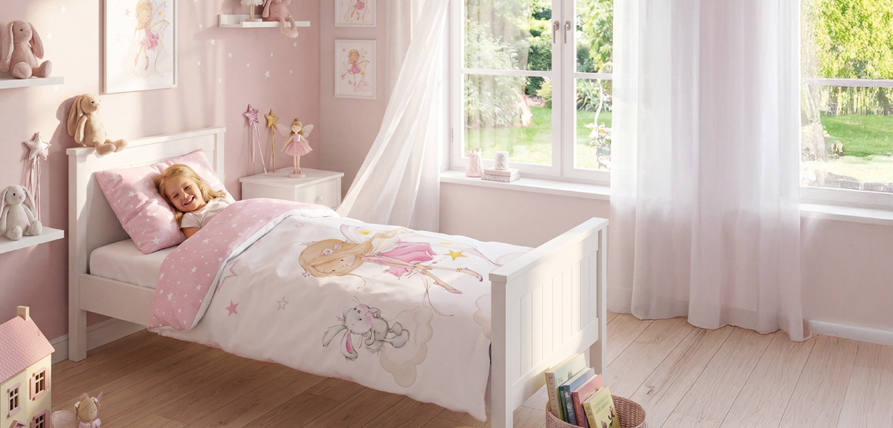 Sommerbettwäsche mit zauberhaftem Feenmotiv in einem hellen, freundlichen Mädchenzimmer. Die rosafarbene Bettwäsche mit Sternen und Fee sorgt für eine leichte, sommerliche Wohlfühlatmosphäre.