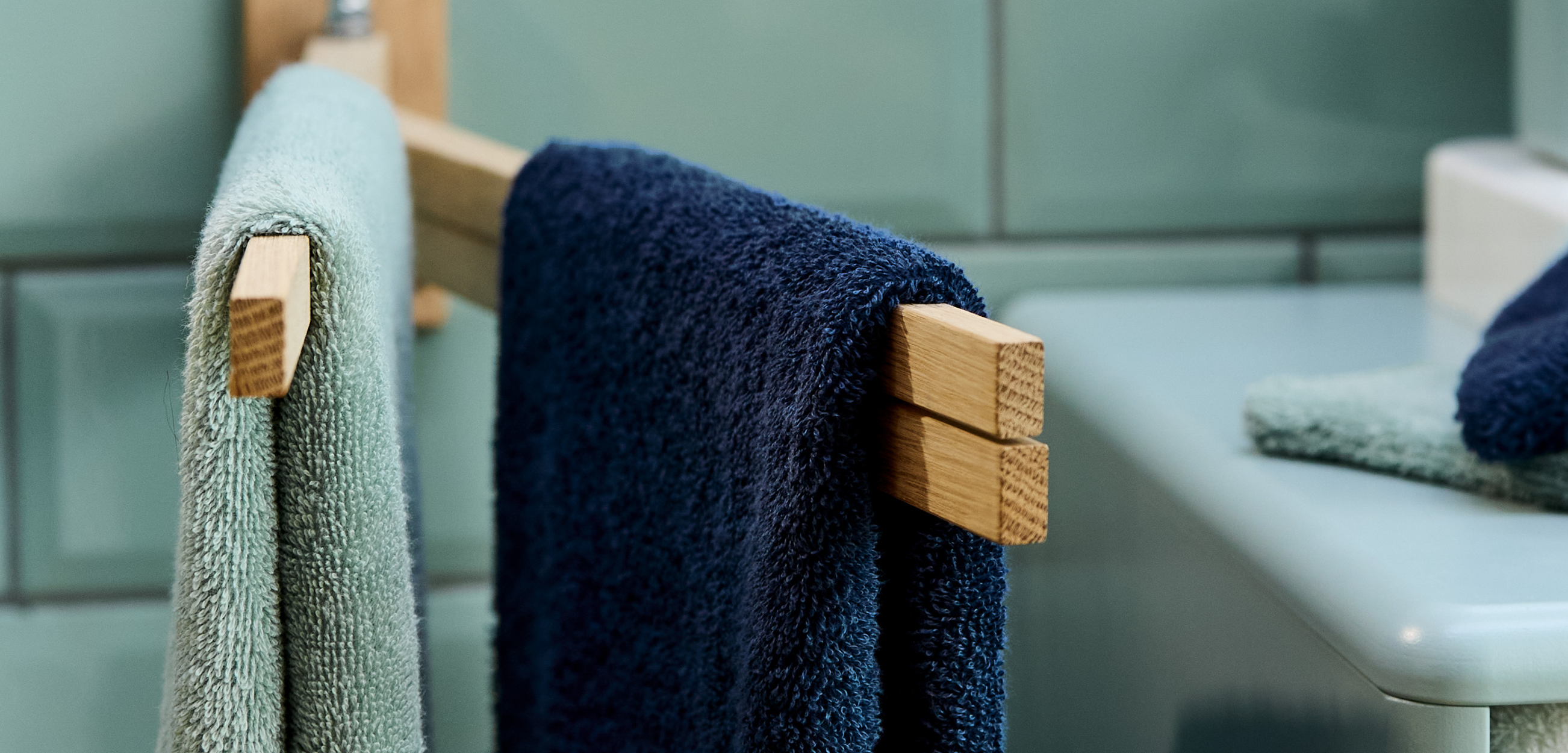 Gästehandtücher in Hellblau und Dunkelblau auf Holzhalterungen im Badezimmer.