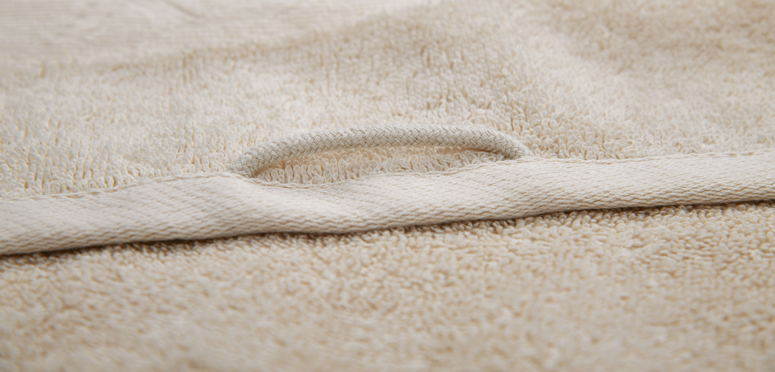 Detailaufnahme eines cremefarbenen Handtuch-Sets mit weicher Frottierstruktur und sauber verarbeiteter, verstärkter Kante. Die Nahaufnahme betont die flauschige Oberfläche und die hochwertige Haptik.
