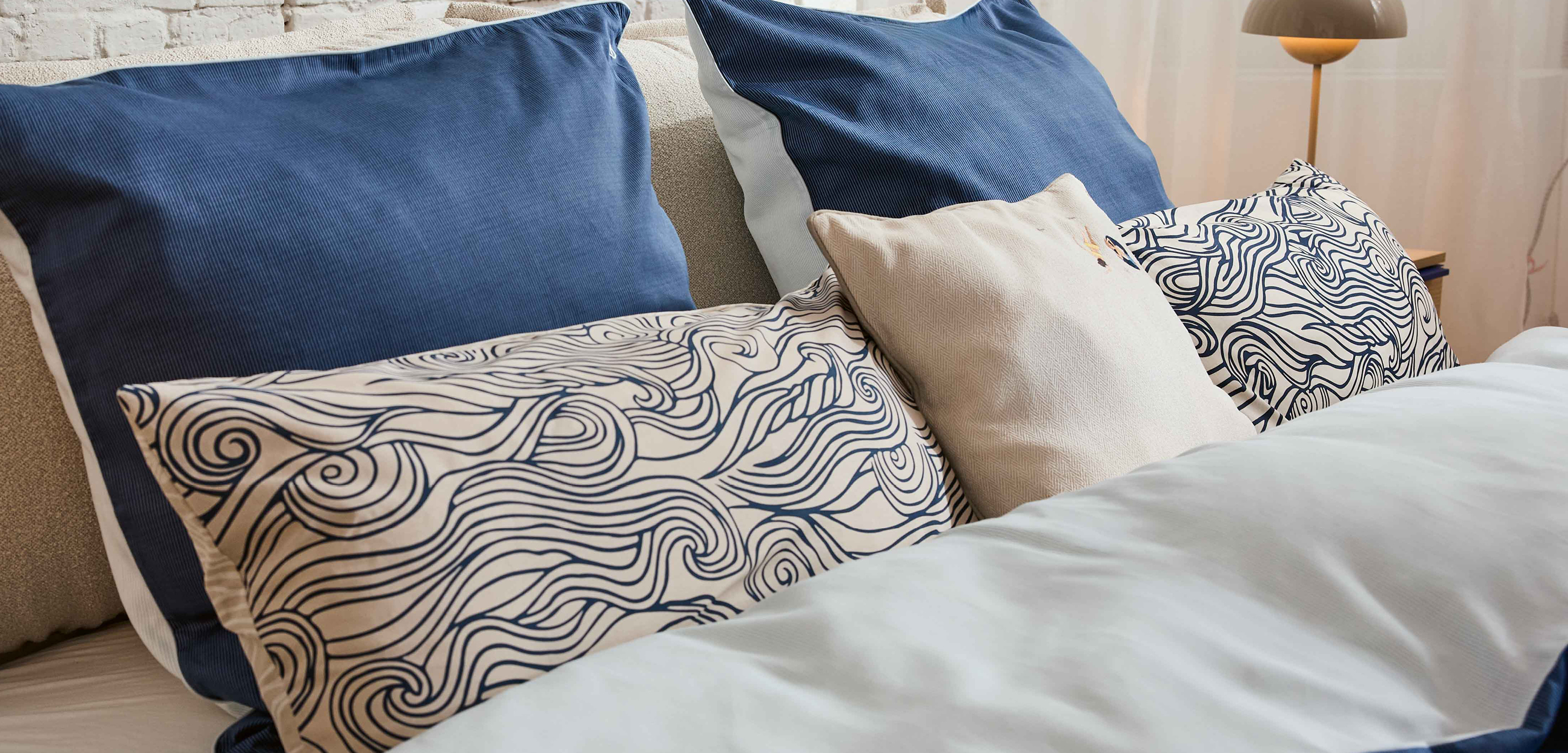 Auf dem Bild sind verschiedene Kissenhüllen auf einem Bett zu sehen.