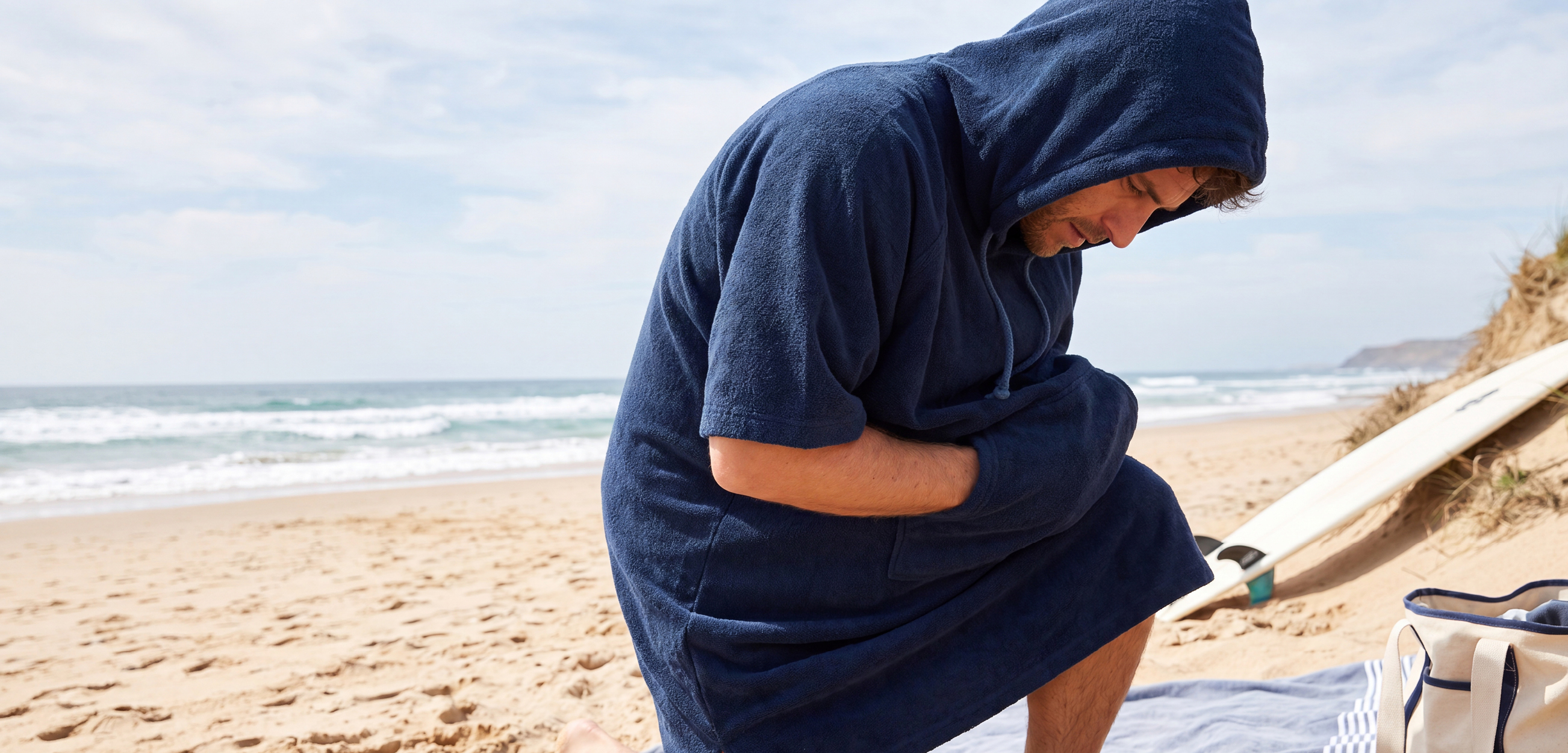 Man kniet glücklich in seinem Surf Poncho