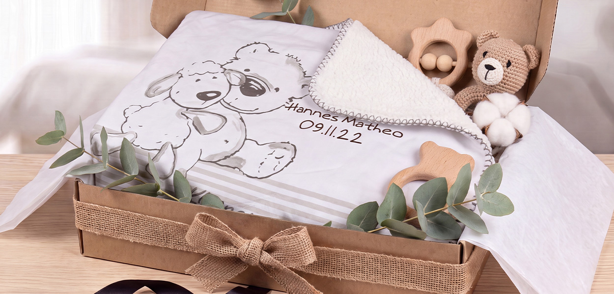Kinderdecke personalisiert : Personalisierte Kinderdecke mit Hundemotiv und dem Namen „Hannes Matheo“ in einem dekorativen Geschenkkorb mit Kuscheltier und Holzspielzeug.