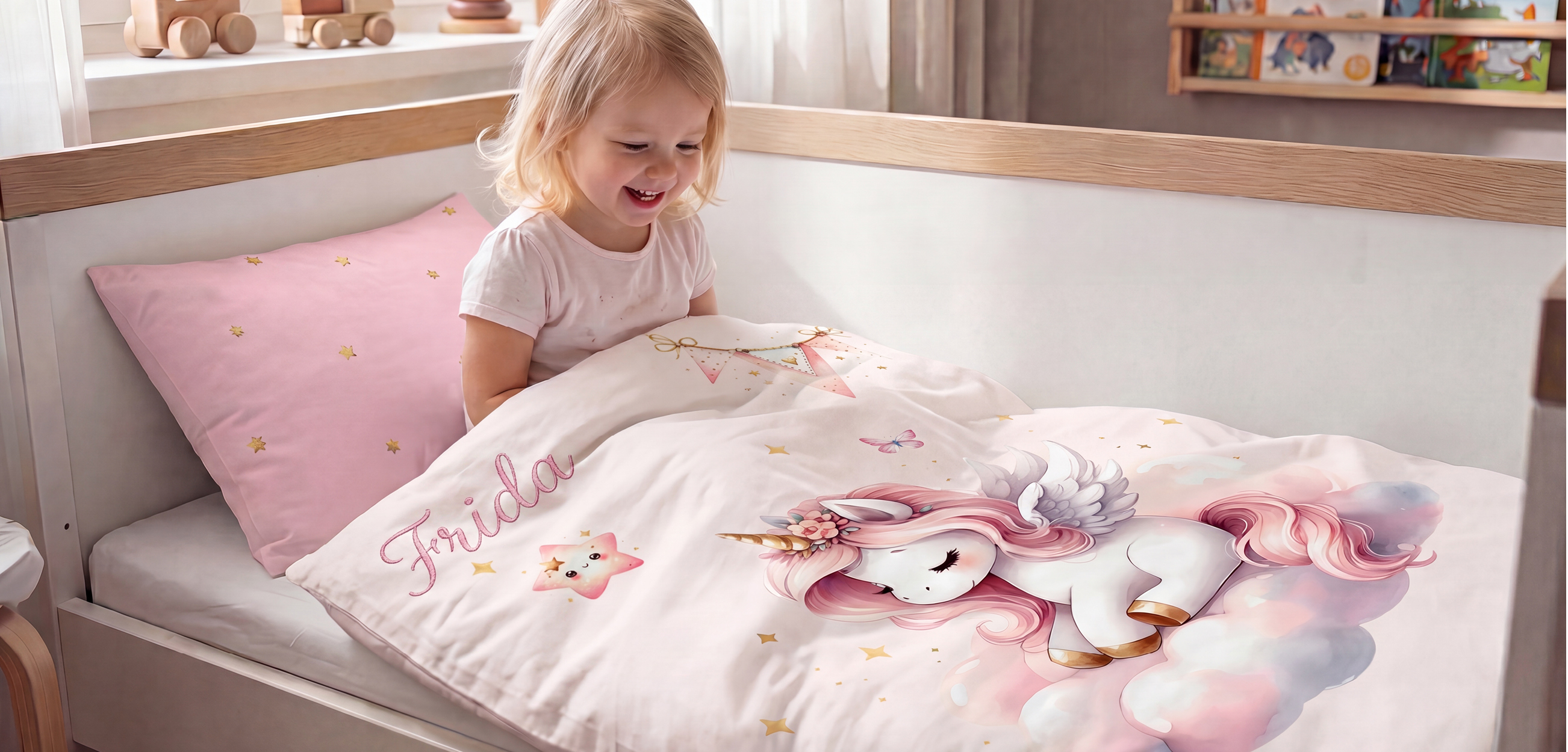 Das Bild zeigt ein Kind im Kinderbett mit einer **personalisierten Einhorn-Bettwäsche**. Auf dem weißen Bettdeckenbezug ist ein großes Einhorn in Rosa- und Pastelltönen sowie der Name **„Frida“** zu sehen. Dazu passt ein rosafarbener Kissenbezug mit goldenen Sternen.