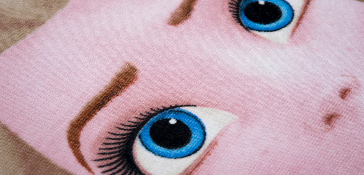 Disney Handtücher: Nahaufnahme eines rosafarbenen Disney-Velourstuchs mit gesticktem Gesichtsmotiv, blauen Augen und weicher, samtiger Materialstruktur.